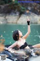 A woman in a black bikini laying in the water.