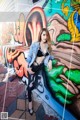 A woman leaning against a wall covered in graffiti.