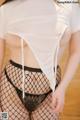 A woman in a white shirt and black fishnet stockings.