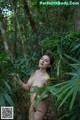 A naked woman standing in the middle of a forest.