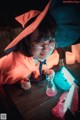 A little girl in a witches hat and glasses sitting at a table.