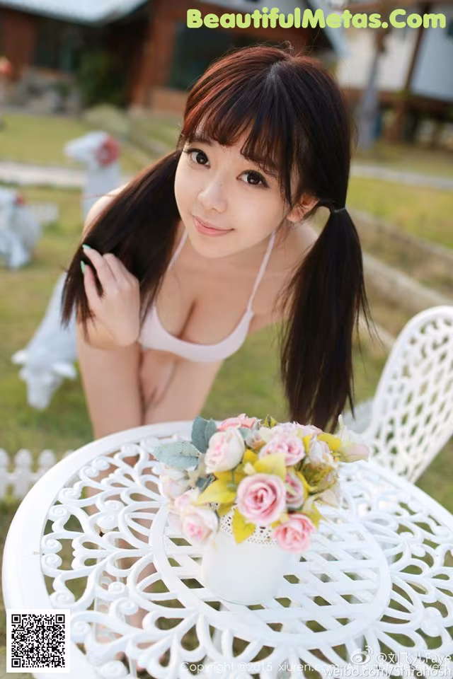 A woman sitting at a table with a vase of flowers.