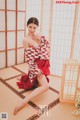 A woman in a red and white kimono sitting on the floor.