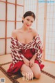 A woman in a red and white kimono sitting on the floor.