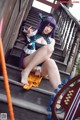 A woman with purple hair sitting on a set of stairs.