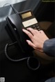 A woman's hand is pressing a button on a telephone.