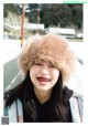 A smiling woman wearing a fur hat in the snow.