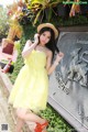 A woman in a yellow dress and straw hat posing for a picture.