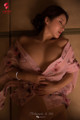 A woman in a pink robe laying on a bed.