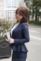 A woman in a blue suit is standing on the street.