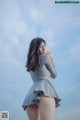 A woman in a gray dress standing on a beach.