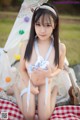 A young woman in a blue and white bikini sitting on a blanket.