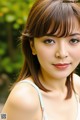 A young woman with long brown hair and bangs posing for a picture.