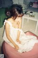 A young girl sitting on a pink ottoman in a room.