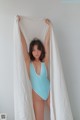 A woman in a blue swimsuit holding a white sheet.