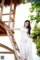 A woman in a white dress standing on a wooden ladder.